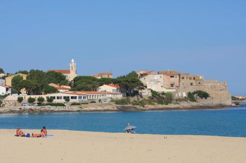 a group of people on a beach near the water at Hotel L'ondine in Algajola