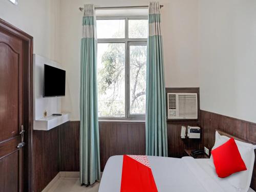 Schlafzimmer mit einem Bett mit grünen Vorhängen und einem Fenster in der Unterkunft Hotel Grand Stay in Ghaziabad