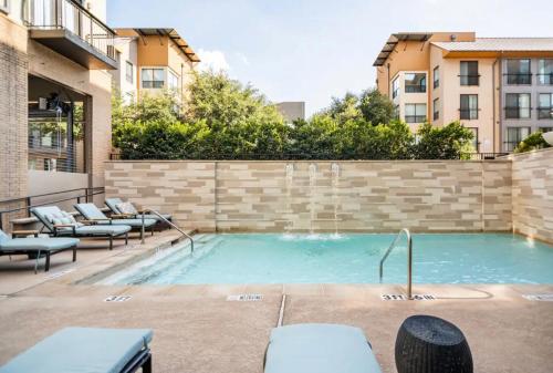 a swimming pool with chairs and a building at Charming 1,100 sq ft apartment near to The Shops at Legacy in Plano