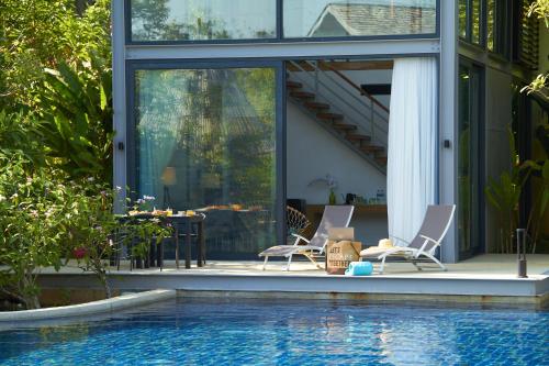 two chairs and a table next to a swimming pool at Island Escape Burasari in Phuket Town