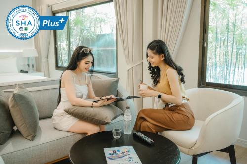 two women sitting on a couch looking at their phones at The Park Hotel in Phitsanulok