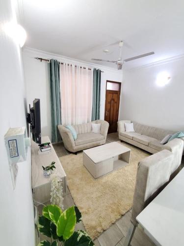 a living room with two couches and a table at Lux Suites Casey's Apartments Bamburi in Bamburi