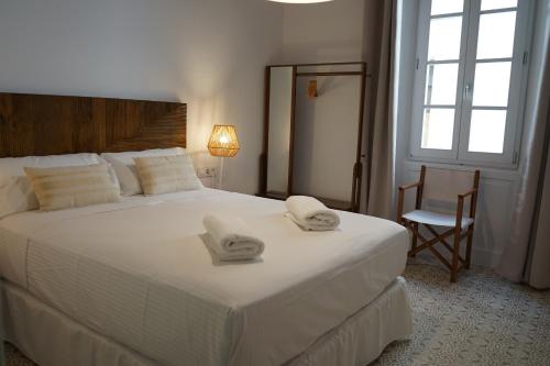 een slaapkamer met een groot wit bed en handdoeken bij Es Mirador Hotel in Ciutadella