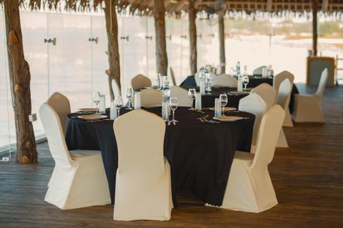 a long table with white chairs and a black table cloth at Giraffe Beach Hotel in Dar es Salaam