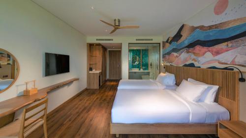 a bedroom with two beds and a painting on the wall at Bellerive Hoi An Resort and Spa in Hoi An
