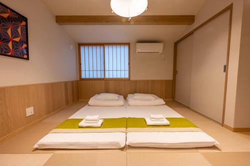 two beds in a room with towels on the floor at Irodori Hotel FUJI in Fukuoka