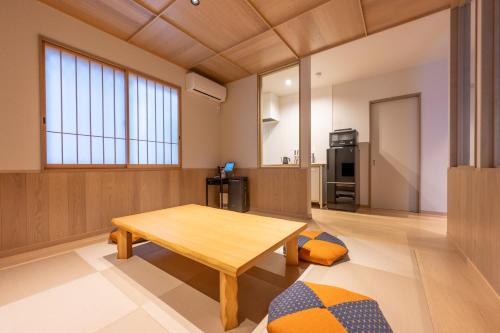 a living room with a wooden table and a kitchen at Irodori Hotel FUJI in Fukuoka