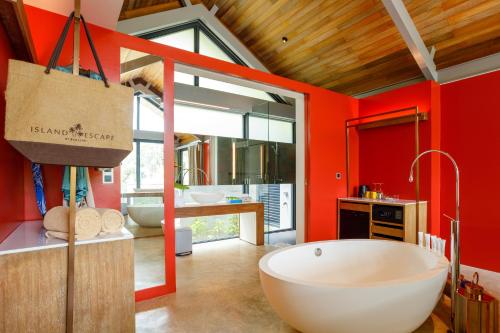 a bathroom with a large tub and red walls at Island Escape Burasari in Phuket Town