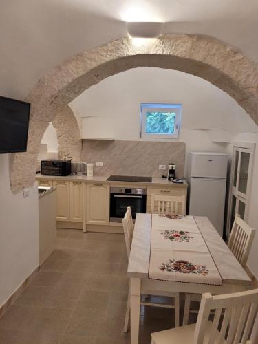 a kitchen and dining room with a table and a kitchen with a stone wall at Trullo il Gelso in San Michele Salentino