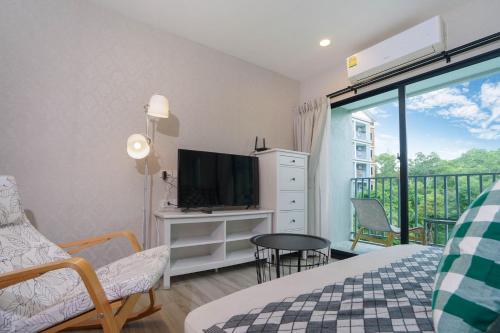 a bedroom with a bed and a tv and a balcony at The Title Residencies Nai Yang - 1 Bedroom Apartment in Nai Yang Beach