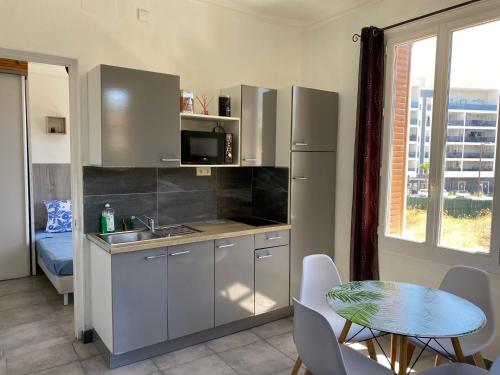 une cuisine avec un évier et une table avec des chaises dans l'établissement Appartement PALOMA Proche Cannes, au Cannet