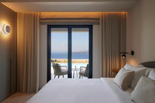 a bedroom with a bed and a view of the ocean at Aernia Suites & Art in Akrotiri