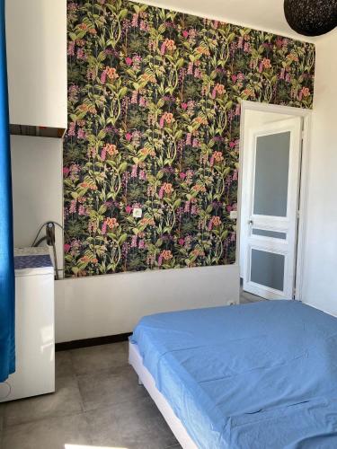 - une chambre avec un lit bleu et un papier peint floral dans l'établissement Appartement PALOMA Proche Cannes, au Cannet