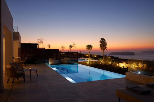 una piscina con tramonto sullo sfondo di Aernia Suites & Art ad Akrotírion