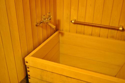 a wooden bath tub with a towel rack on a wall at Nara Hotel in Nara