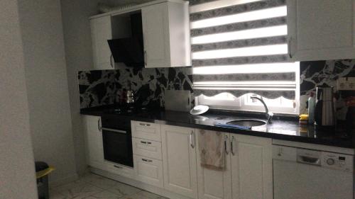 een keuken met witte kasten, een wastafel en een raam bij MY HOUSE in Yomra