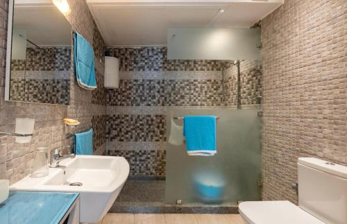 y baño con lavabo y ducha con toallas azules. en Appartement familial paisible, en Tánger