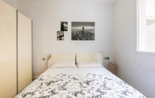 1 cama en una habitación blanca con 2 cuadros en la pared en Appartement familial paisible, en Tánger