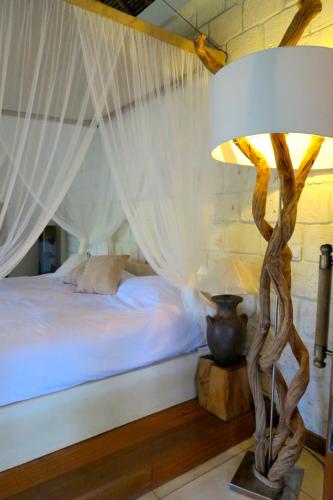 a bedroom with a bed and a table with a lamp at La Cabane in Jimbaran