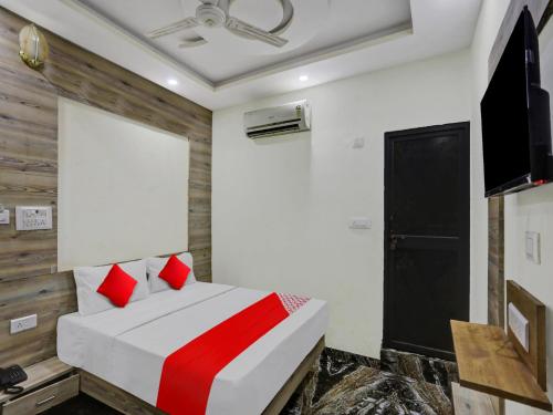 a bedroom with a bed with red pillows and a television at OYO Flagship 80984 Hotel Siddhi Vinayak in Kānpur
