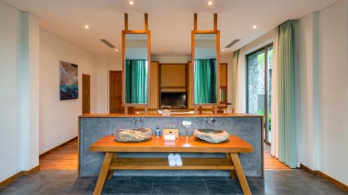 a dining room with a table and a mirror at Bellerive Hoi An Resort and Spa in Hoi An