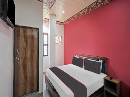 a bedroom with a red wall and a bed at Collection O 81112 Hotel Joyous in Ghaziabad