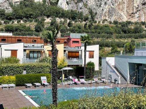 a hotel with a swimming pool and palm trees at Outdooredo Garda Torbole in Nago-Torbole