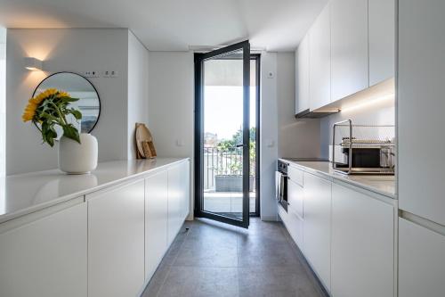 a kitchen with white cabinets and a mirror at BONFIM LIVING - Great location, al fresco dining and free private parking in Porto