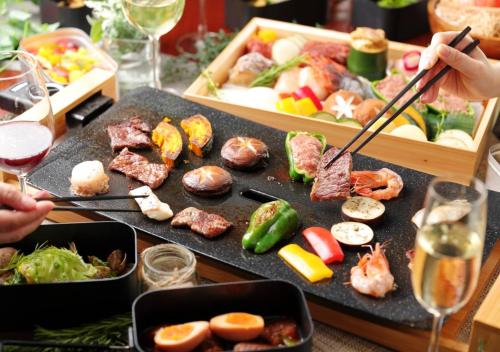 a table topped with plates of food and glasses of wine at GLAMDAY PORT in Atami