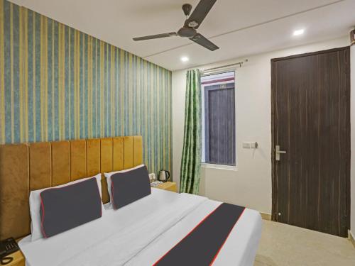 1 dormitorio con 1 cama grande y ventilador de techo en OYO Flagship Cosmo Inn en Allahābād