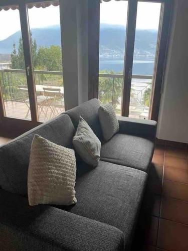 a couch with two pillows sitting in a room with windows at Casa Verbanella in Minusio