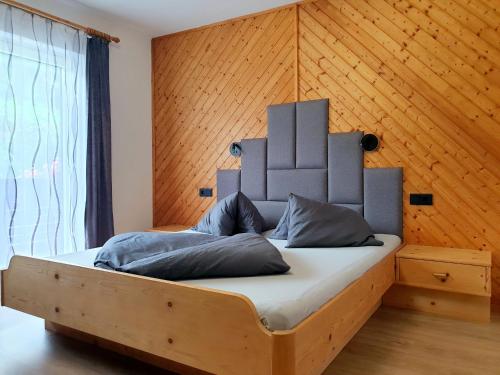 a bed in a room with a wooden wall at Apartment Steirawohnzimmer in Haus im Ennstal