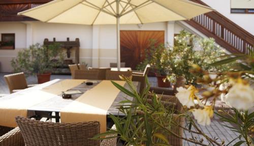 a dining room with a table with an umbrella at Pension zur Sonne in Illmitz