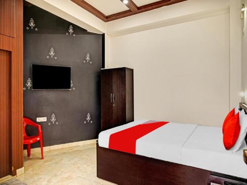a bedroom with a bed and a red chair at OYO Flagship 81208 Laxmi Guest House Jadavpur in Kolkata