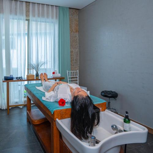 a person laying in a bed with a sink at Bellerive Hoi An Resort and Spa in Hoi An