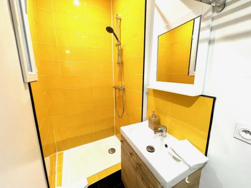La salle de bains jaune est pourvue d'un lavabo et d'une douche. dans l'établissement Loft NYC - Hyper centre, à Nantes
