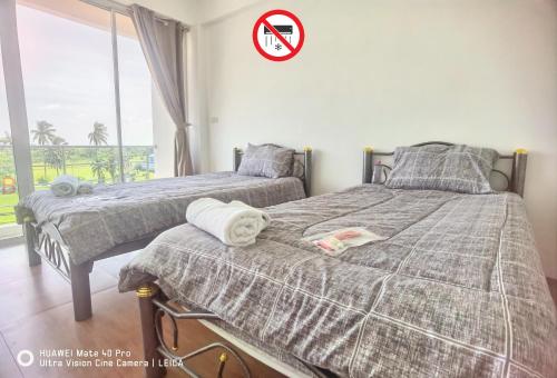 two beds in a bedroom with a sign on the wall at YYK Hostel 24H in Ban Khlong Krang