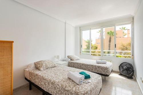 two beds in a room with a window at La Casa Alegre in Alicante