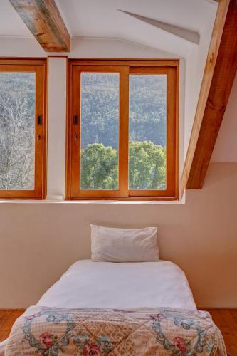 a bedroom with a bed and two windows at Somerset Gift Getaway Farm in Swellendam