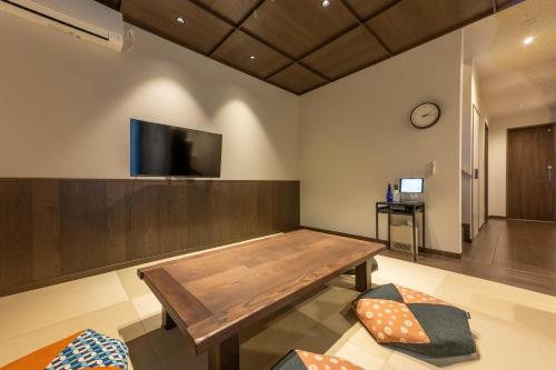 a room with a wooden table and a tv on the wall at 彩ホテル 紺 in Fukuoka