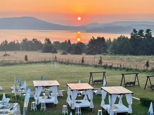a group of tables and chairs in a field with the sunset at Family Hotel Eterno in Tsigov Chark