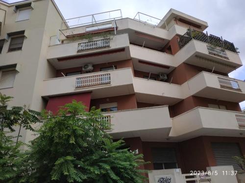 een appartementencomplex met balkons en een boom bij Appartamento Sole Blu in Alghero