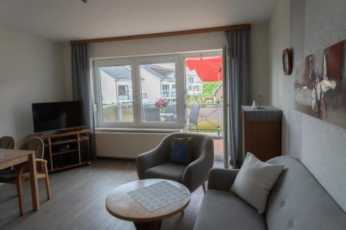 een woonkamer met een bank, een stoel en een raam bij Appartementhaus Christel in Grömitz