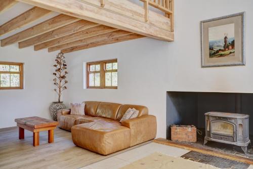 a living room with a leather couch and a fireplace at Somerset Gift Getaway Farm in Swellendam