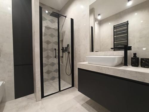 een badkamer met een glazen douche en een wastafel bij GOLD APARTMENTS Capital Towers in Rzeszów