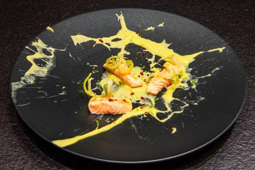 a black plate with food on it with yellow sauce at Hotel Montchalet in Ortisei