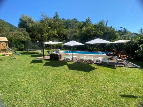 a backyard with a swimming pool with umbrellas at CASA DRENCOVA SRL in Berzasca