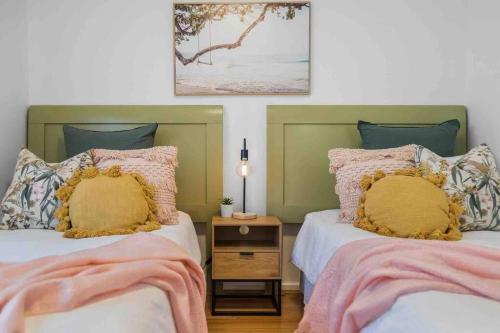 a bedroom with two beds with pink and yellow pillows at Stunning 2BR CBD Apartment next to King's Park in Perth