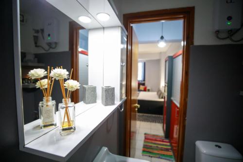 La salle de bains est pourvue d'un miroir et de vases fleuris. dans l'établissement Adriana's downtown studio-parking lot included, à Patras