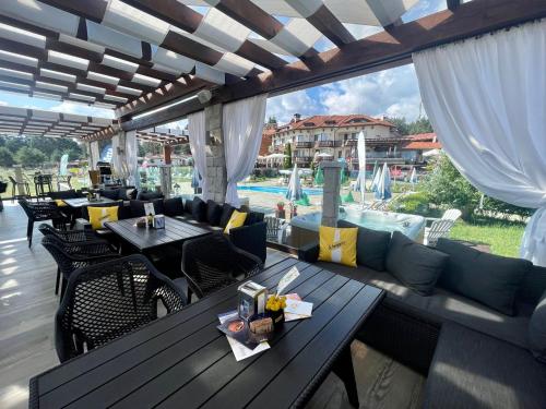 a patio with couches and tables and a pool at Family Hotel Eterno in Tsigov Chark